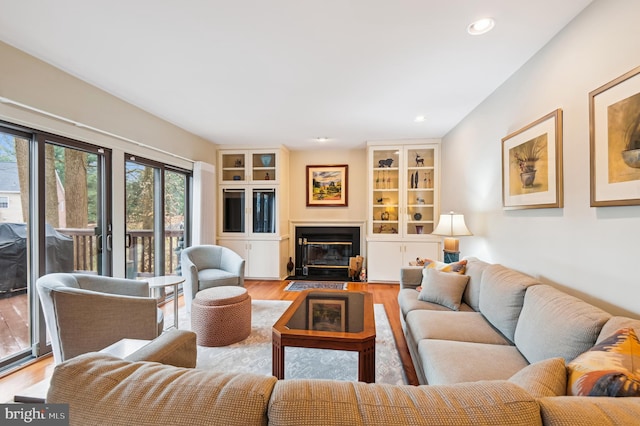 living area featuring a fireplace with flush hearth, wood finished floors, and recessed lighting