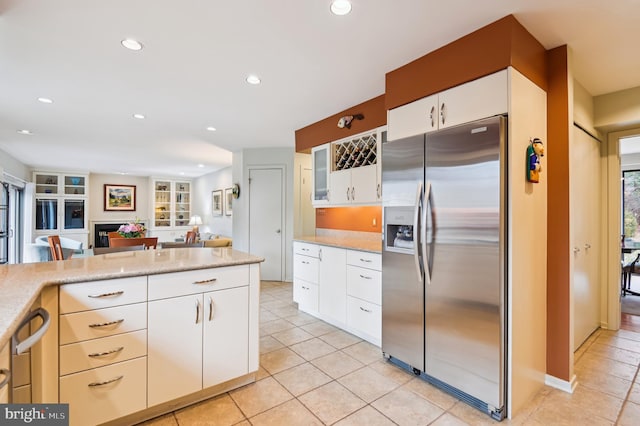 kitchen featuring light tile patterned floors, stainless steel fridge with ice dispenser, light countertops, a fireplace, and recessed lighting