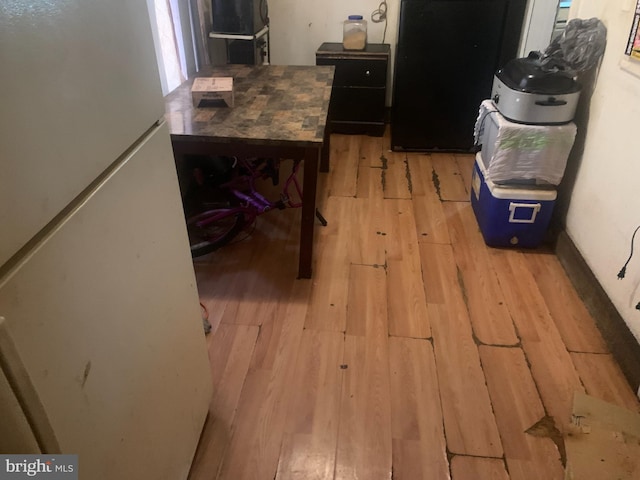 interior space with white fridge, black refrigerator, and light wood-type flooring