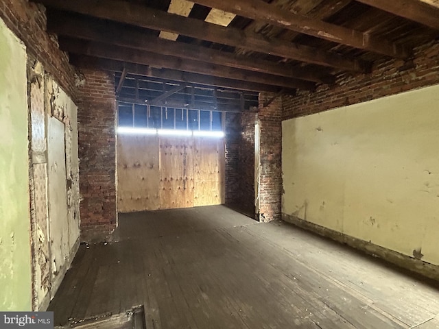 misc room with hardwood / wood-style flooring and brick wall