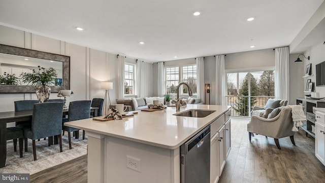 kitchen with sink, dark wood-type flooring, a kitchen island with sink, white cabinetry, and stainless steel dishwasher