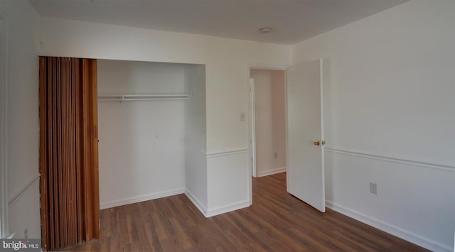 unfurnished bedroom featuring dark hardwood / wood-style flooring and a closet