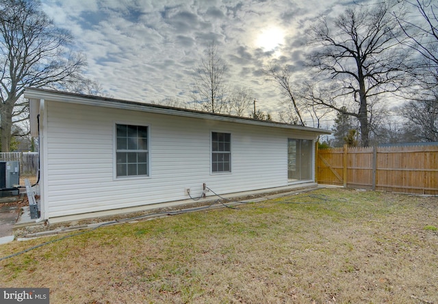 back of property featuring central air condition unit and a lawn