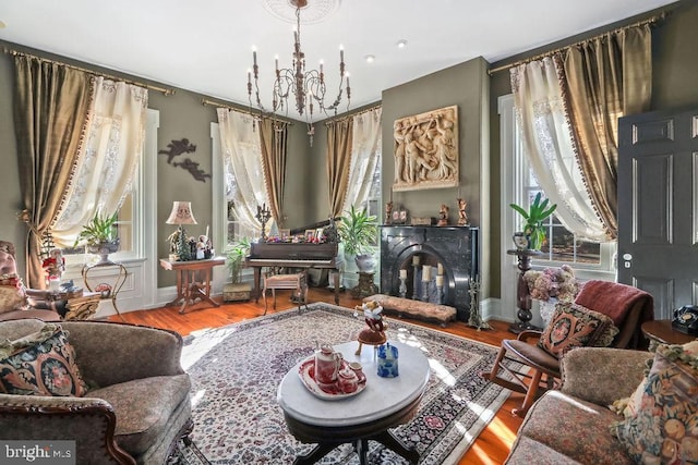 living area with plenty of natural light, hardwood / wood-style floors, and an inviting chandelier