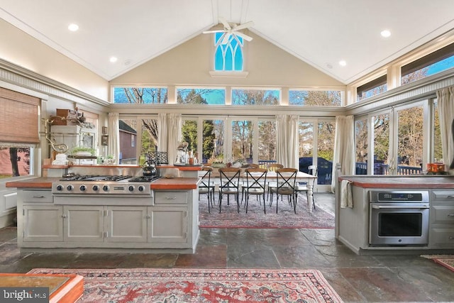 kitchen with butcher block counters, high vaulted ceiling, and appliances with stainless steel finishes