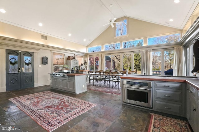 kitchen featuring gray cabinets, ceiling fan, appliances with stainless steel finishes, high vaulted ceiling, and french doors