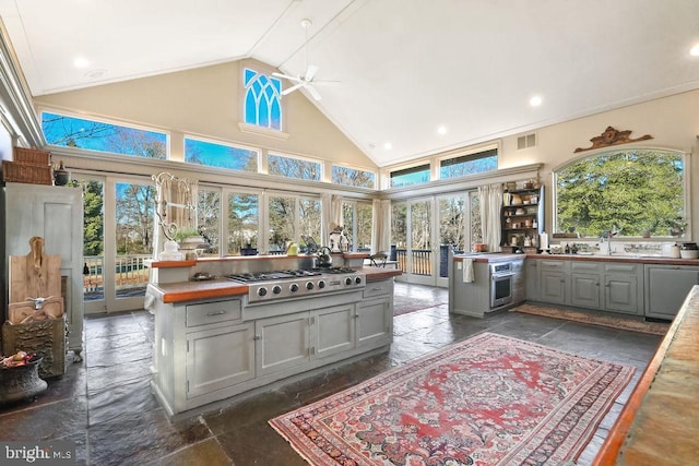 kitchen with butcher block countertops, appliances with stainless steel finishes, gray cabinetry, and high vaulted ceiling