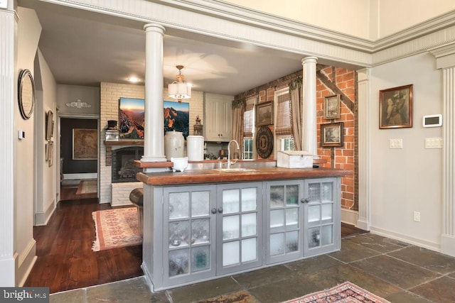 bar featuring decorative columns, a brick fireplace, and sink