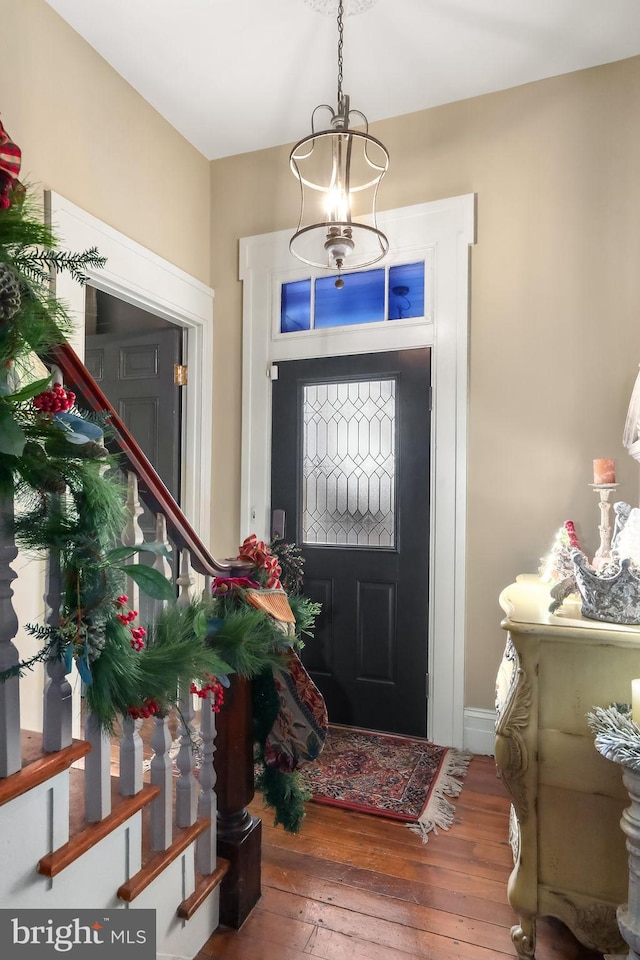 foyer entrance with hardwood / wood-style floors and a chandelier