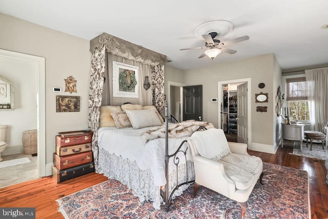 bedroom featuring ensuite bath, dark hardwood / wood-style floors, ceiling fan, and a spacious closet