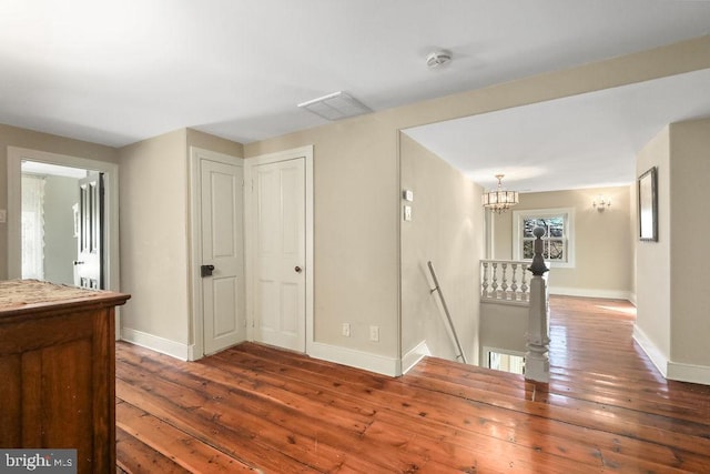 corridor featuring hardwood / wood-style floors and an inviting chandelier