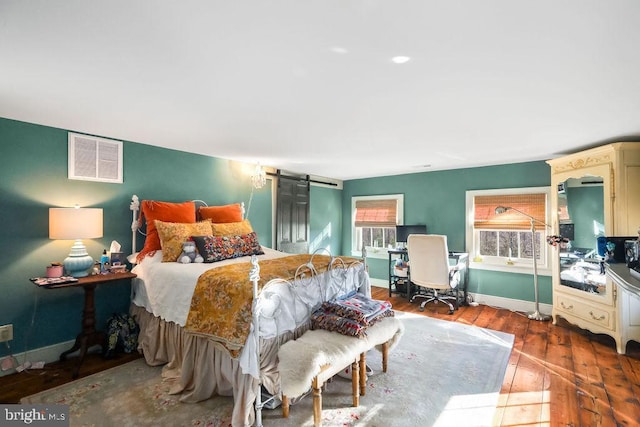 bedroom featuring wood-type flooring and a barn door