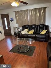 living room featuring ceiling fan and dark hardwood / wood-style flooring