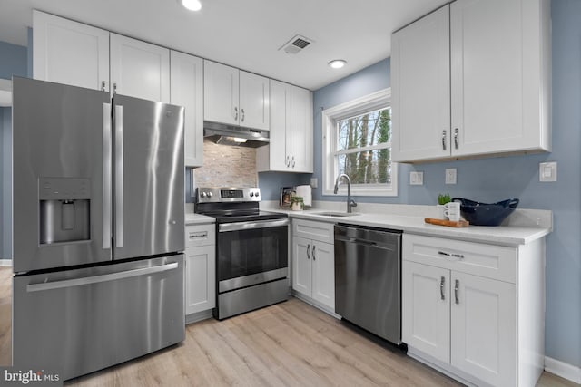 kitchen featuring stainless steel appliances, light countertops, visible vents, a sink, and under cabinet range hood