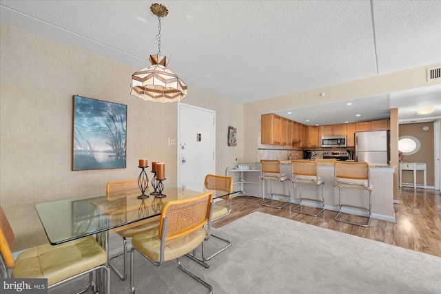 dining space with a textured ceiling and light wood-type flooring