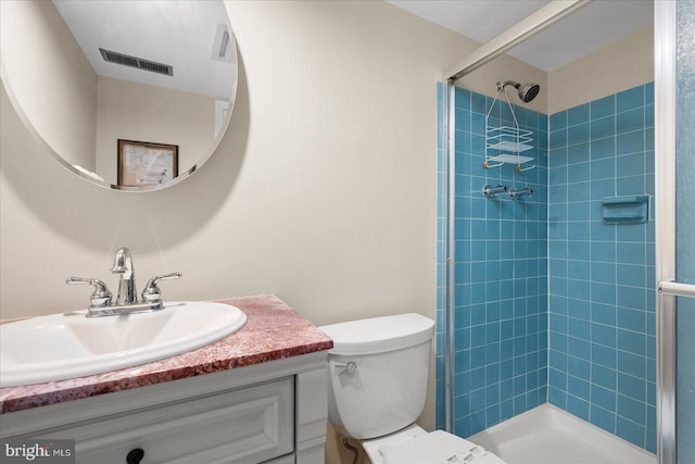 bathroom with vanity, toilet, and a tile shower