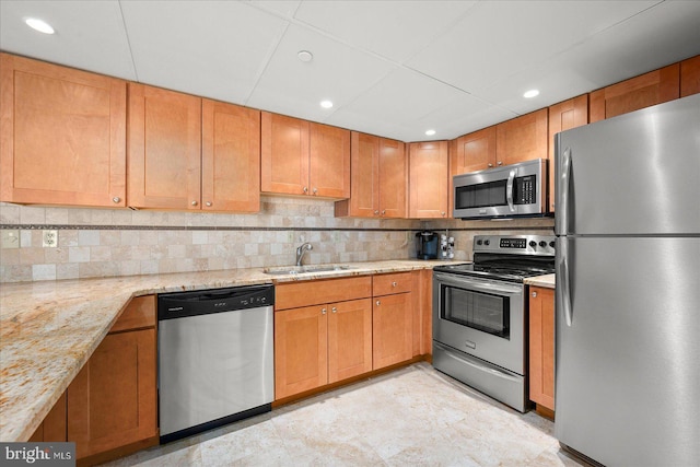 kitchen with stainless steel appliances, sink, backsplash, and light stone counters