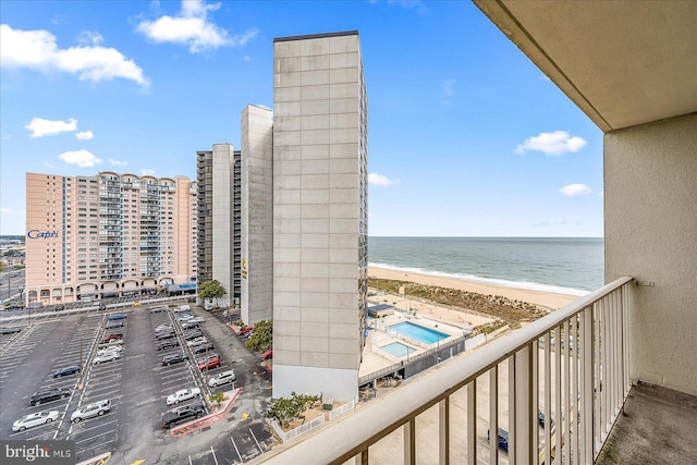 balcony with a water view and a view of the beach