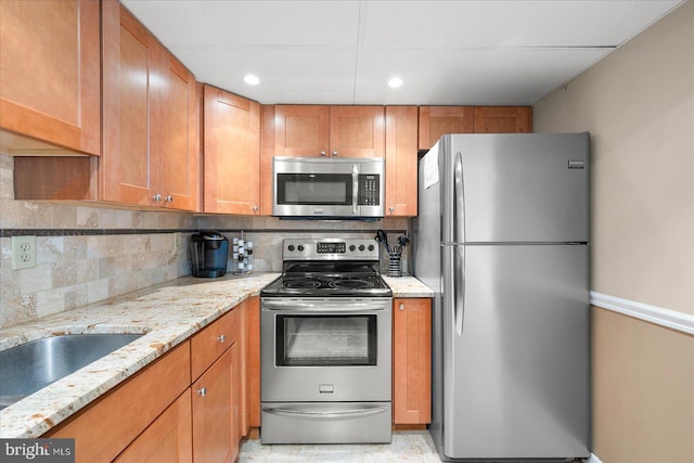 kitchen with stainless steel appliances, light stone countertops, and backsplash