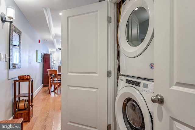 clothes washing area with stacked washer / dryer and light hardwood / wood-style flooring