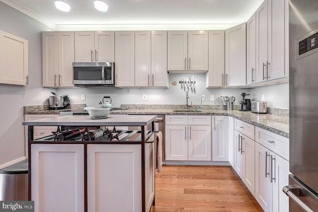 kitchen with sink, refrigerator, light hardwood / wood-style flooring, light stone countertops, and white cabinets