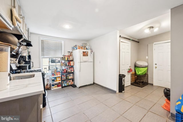 kitchen with white fridge, light tile patterned floors, and light stone countertops