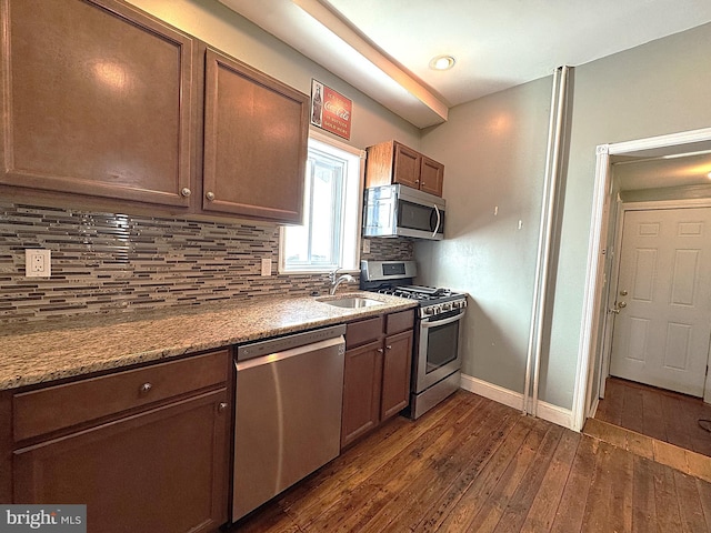 kitchen featuring sink, backsplash, dark wood-type flooring, and appliances with stainless steel finishes