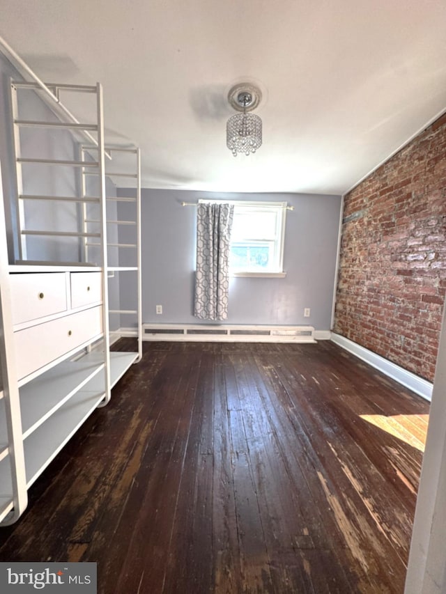 unfurnished bedroom featuring brick wall, hardwood / wood-style floors, and a baseboard heating unit