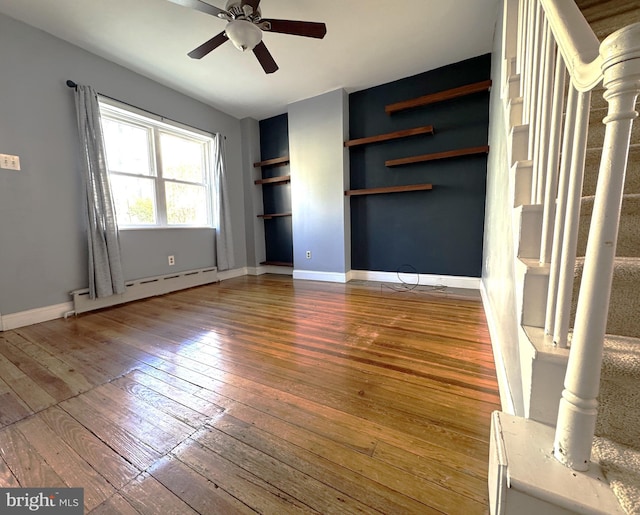 unfurnished living room with a baseboard heating unit, hardwood / wood-style flooring, built in features, and ceiling fan