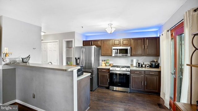 kitchen with dark hardwood / wood-style flooring, stainless steel appliances, kitchen peninsula, and dark brown cabinets