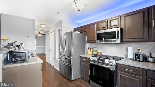 kitchen featuring ceiling fan, appliances with stainless steel finishes, dark brown cabinetry, and dark hardwood / wood-style flooring