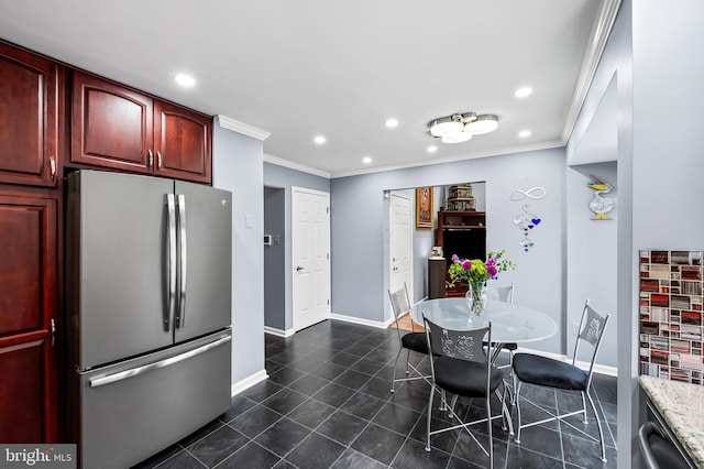 kitchen featuring ornamental molding, light stone counters, dark tile patterned flooring, and stainless steel refrigerator