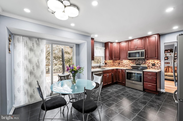 kitchen featuring tasteful backsplash, ornamental molding, appliances with stainless steel finishes, and sink