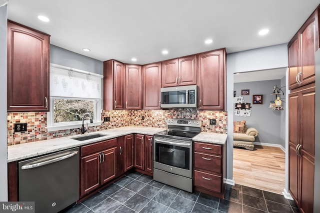 kitchen with light stone counters, appliances with stainless steel finishes, sink, and decorative backsplash