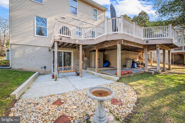 rear view of house with a wooden deck, a fire pit, a patio, and a lawn