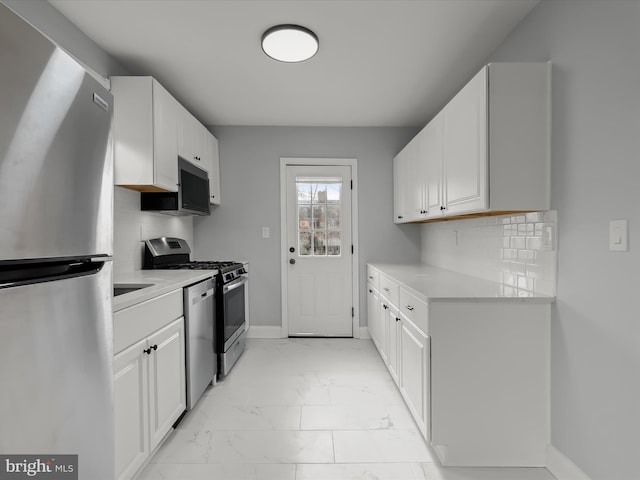 kitchen with baseboards, marble finish floor, stainless steel appliances, light countertops, and white cabinetry