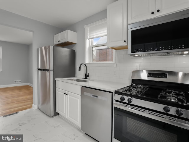 kitchen with visible vents, white cabinetry, marble finish floor, light countertops, and appliances with stainless steel finishes