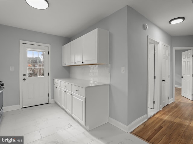 kitchen featuring marble finish floor, light countertops, decorative backsplash, and white cabinets