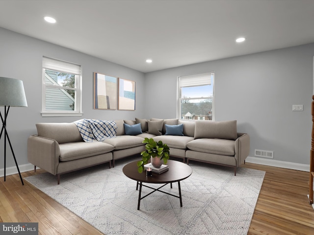 living room with recessed lighting, visible vents, baseboards, and wood finished floors