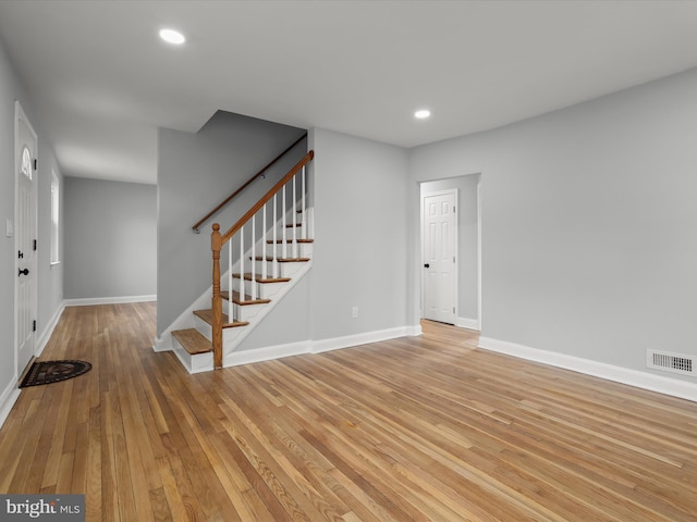 interior space with stairway, light wood-style flooring, visible vents, and baseboards