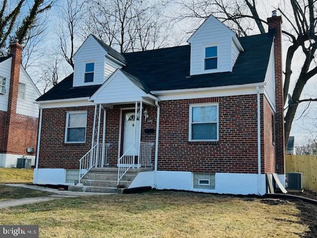 new england style home featuring brick siding, a chimney, a front lawn, and central air condition unit