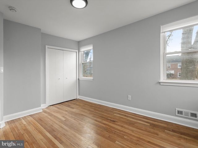 unfurnished bedroom with light wood finished floors, a closet, visible vents, and baseboards