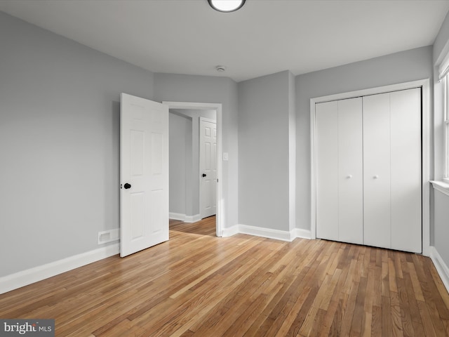 unfurnished bedroom featuring light wood-type flooring, visible vents, baseboards, and a closet