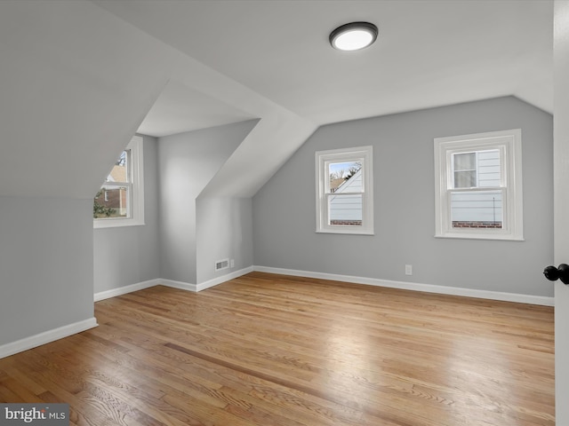 bonus room with lofted ceiling, light wood-style floors, visible vents, and baseboards