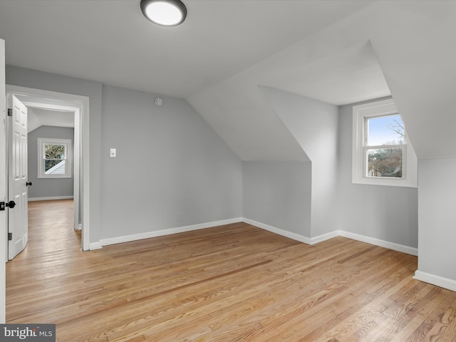 additional living space with light wood-style floors, lofted ceiling, and baseboards