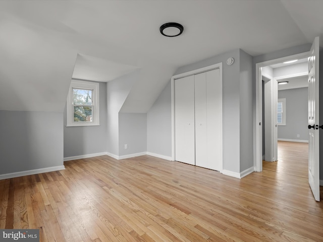 bonus room with lofted ceiling, light wood-type flooring, and baseboards