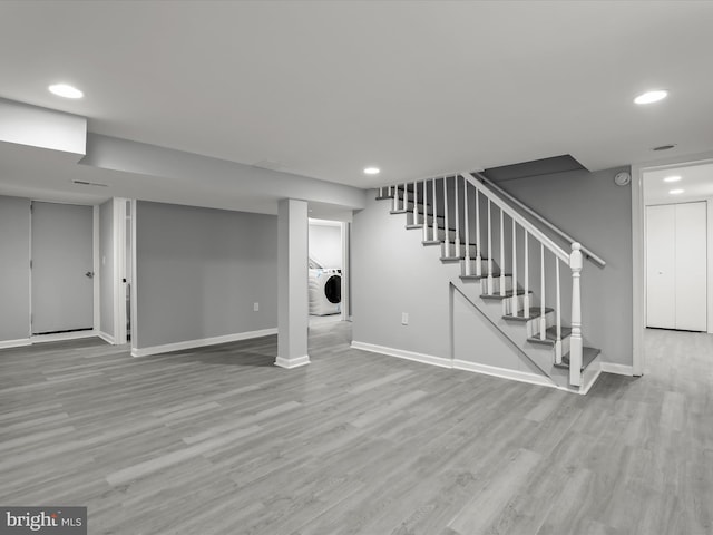 finished basement with washer / clothes dryer, stairway, light wood-style flooring, and baseboards