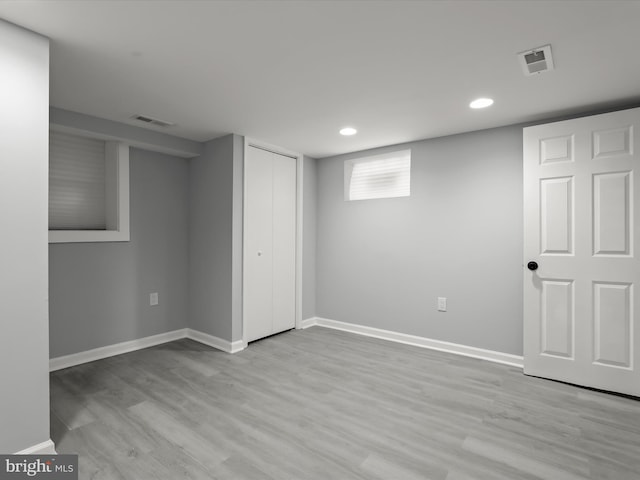 basement featuring visible vents, light wood finished floors, and baseboards