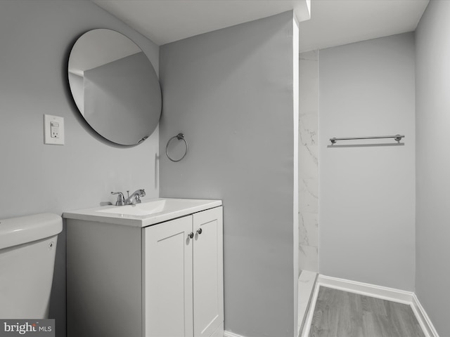 bathroom with toilet, baseboards, wood finished floors, and vanity