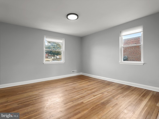 unfurnished room with light wood-style flooring, visible vents, and baseboards